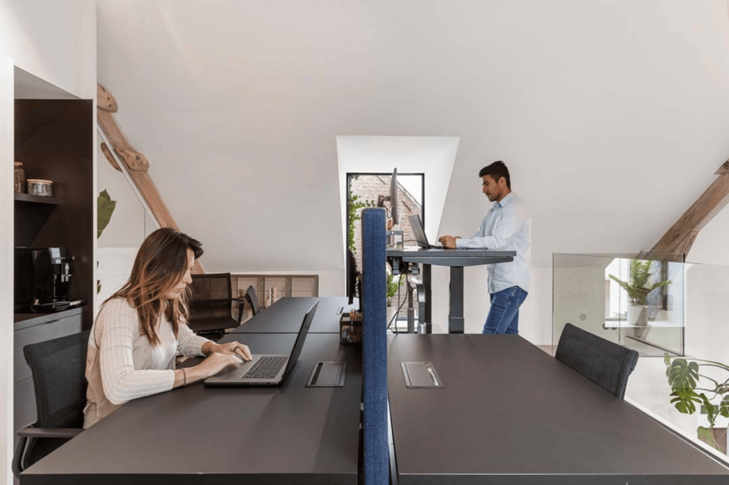 Office design by Buro Project with a modern workspace featuring a bench desk, acoustic partition, and sit-stand desk.
