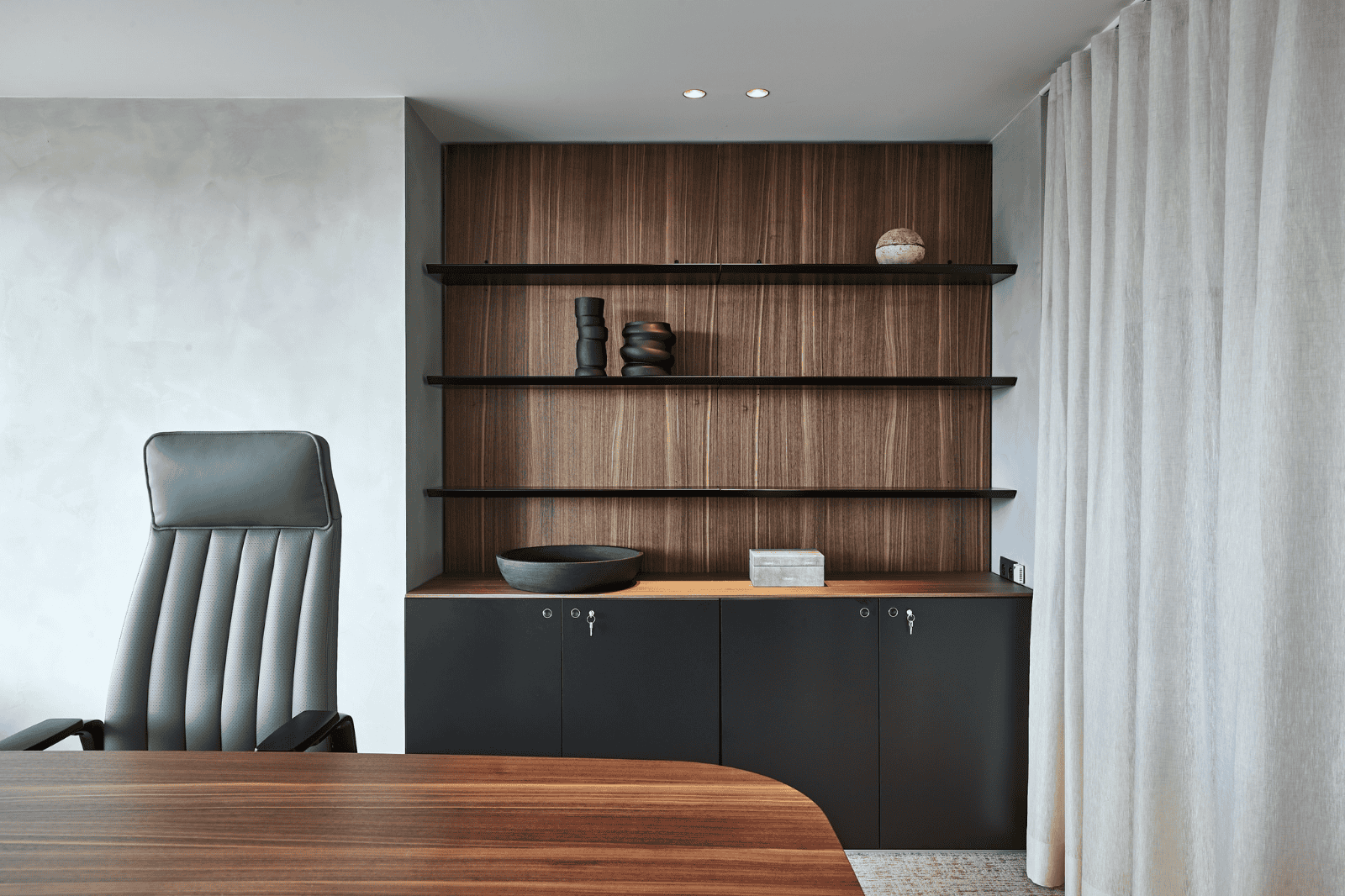 Office design by Buro Project in a sleek executive office with wooden wall cabinets, storage space, and an ergonomic office chair.